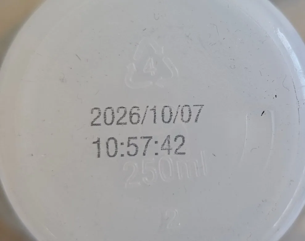 Date and time code printed with thermal inkjet on a white plastic lid, recycling mark 4