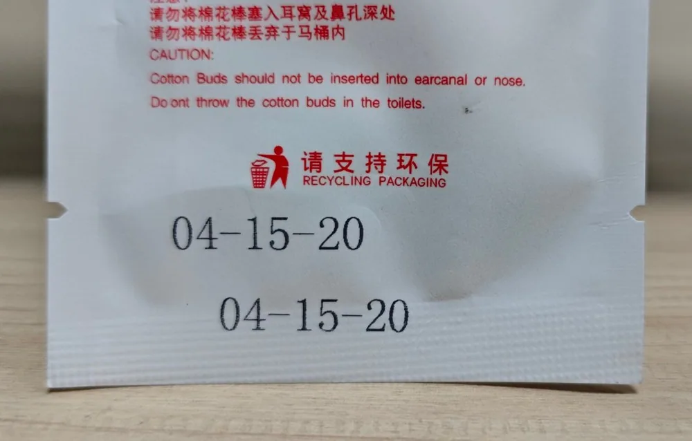 A two-line date code printed on a white printed retail pouch, below the recycling logo and the caution text