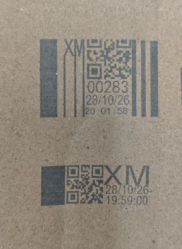 Two codes printed with our own cartridges on the same strip of corrugated board: the one-inch mark stacked across several lines in a taller block, the half-inch mark laid out along a single low band